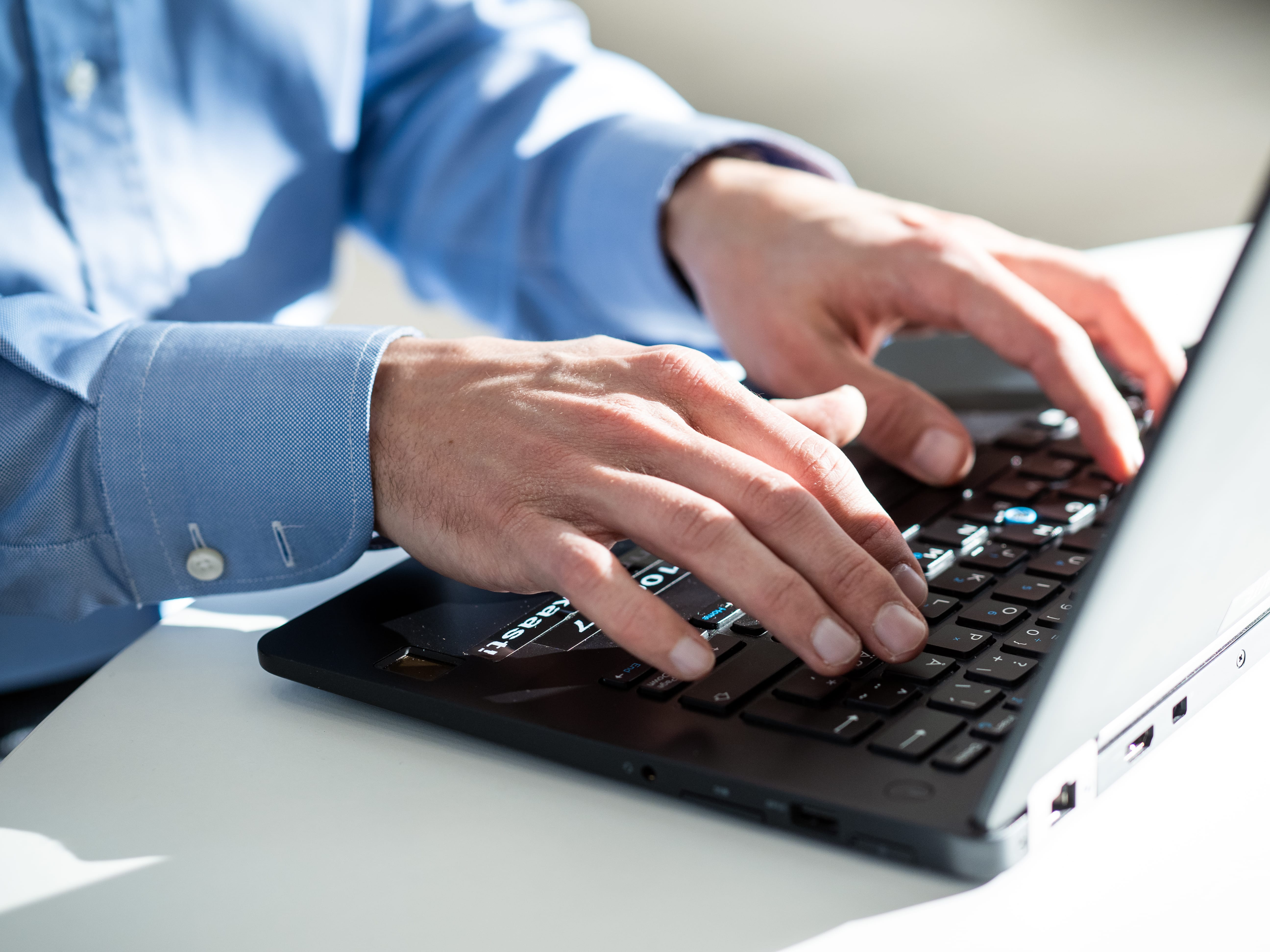 A man's hands on a laptop keyboard.