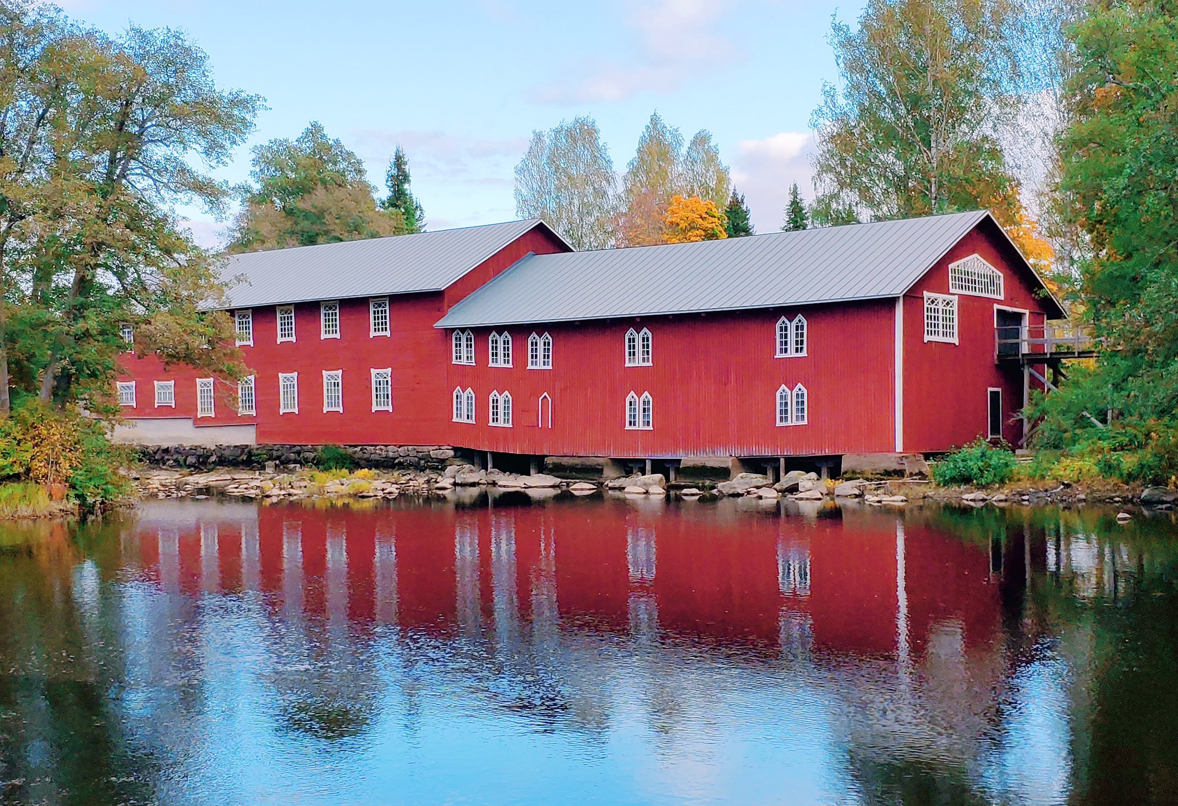 Red wooden building near water.