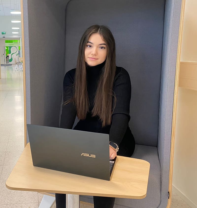 Alexandra Marin istuu kannettavan tietokoneen kanssa tuolilla.