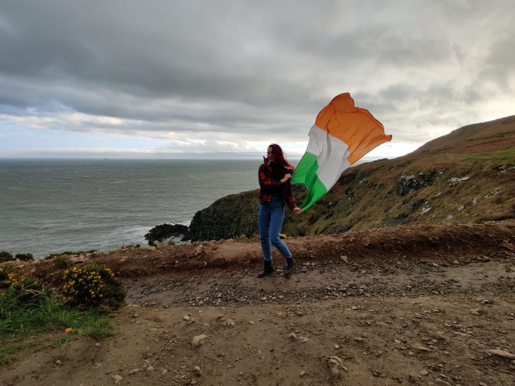 Emilia Hasa kävelee kalliolla heiluttaen Irlannin lippua.