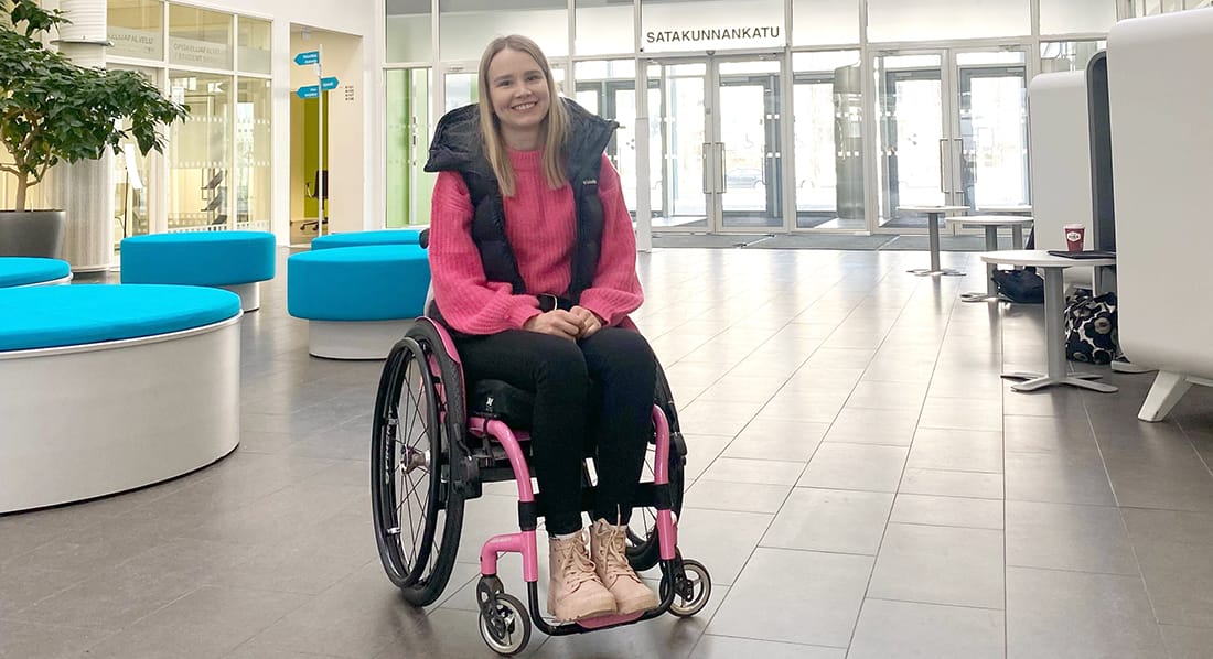 Eveliina Salonen istuu pyörätuolissa Porin kampuksen aulassa.