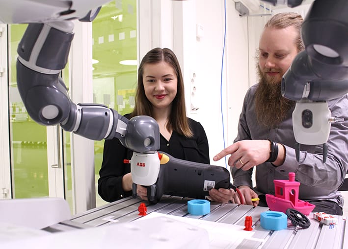 Opiskelijat testaamassa Yumi-käsivarsirobottia RoboAI:n laboratoriossa.