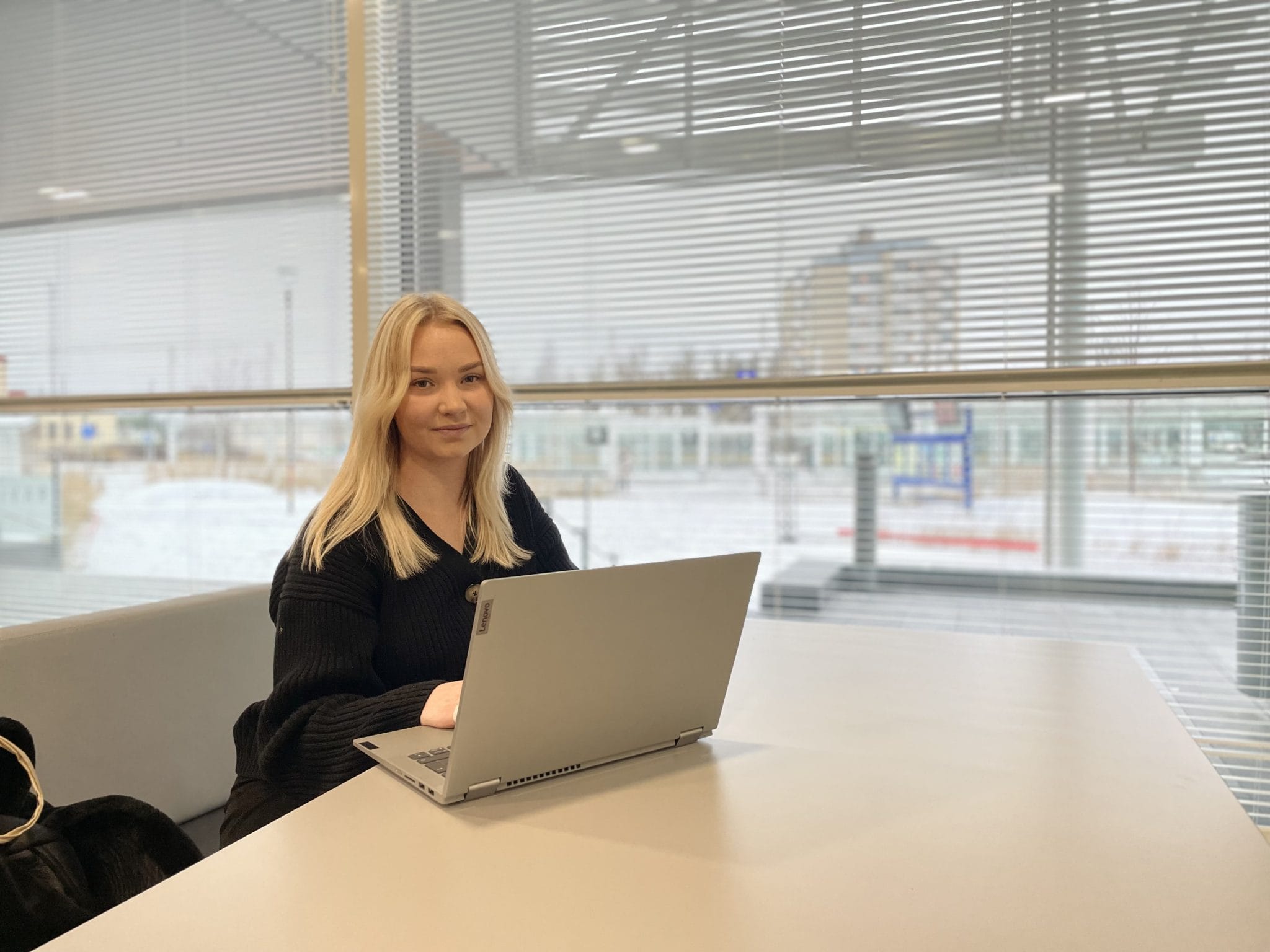 Jenniina poseeraamassa tietokoneen äärellä.