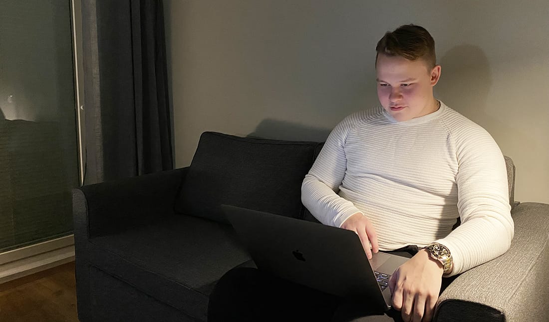 Juho Grönroos sohvalla kannettavan tietokoneen kanssa