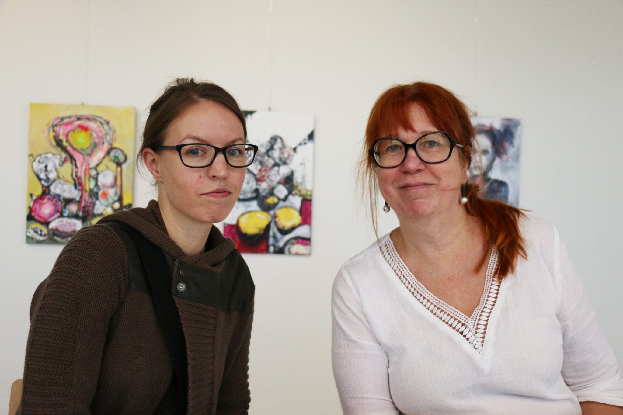 Kaksi SAMK Kankaanpään opiskelijaa poseeraavat taidenäyttelynsä edessä.