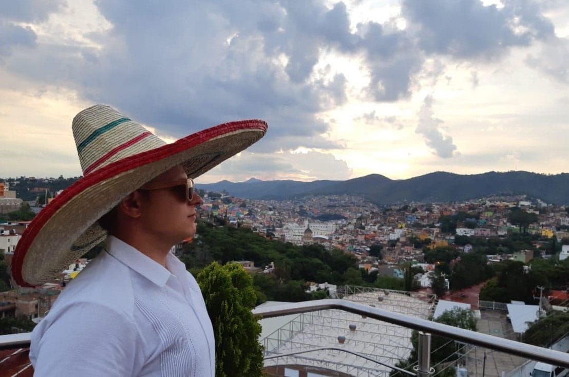 Kristen Liivrand meksikolaisessa maisemassa iso hattu päässä, taustalla kaupunki