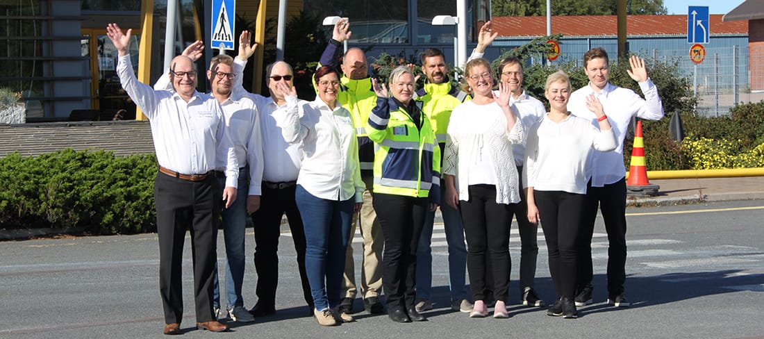 Port Activity Appin kehittäjätiimi seisoo rakennuksen pihassa ja heiluttaa.