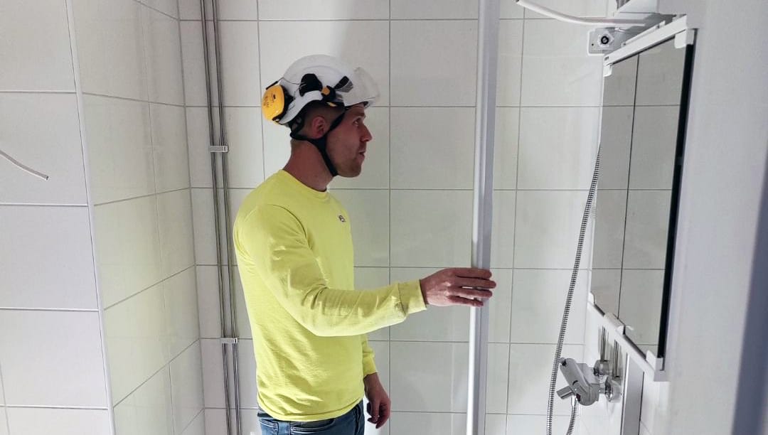 Markus Kallunki rakennusvarusteissa kylpyhuoneessa.
