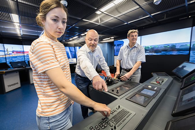Nainen ja kaksi miestä merenkulun simulaatiotilassa.