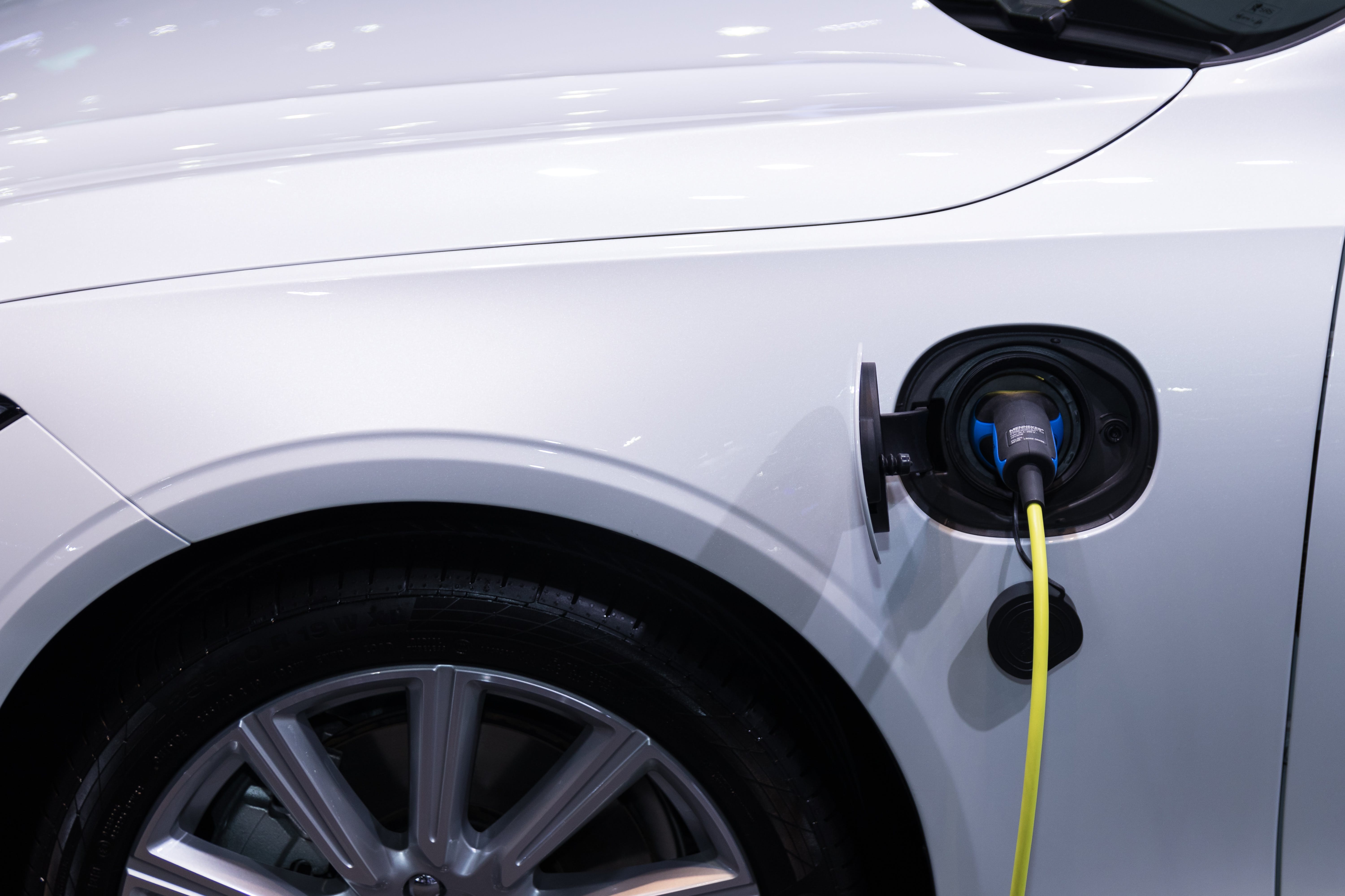 The white electric car has a charging cable on the side.