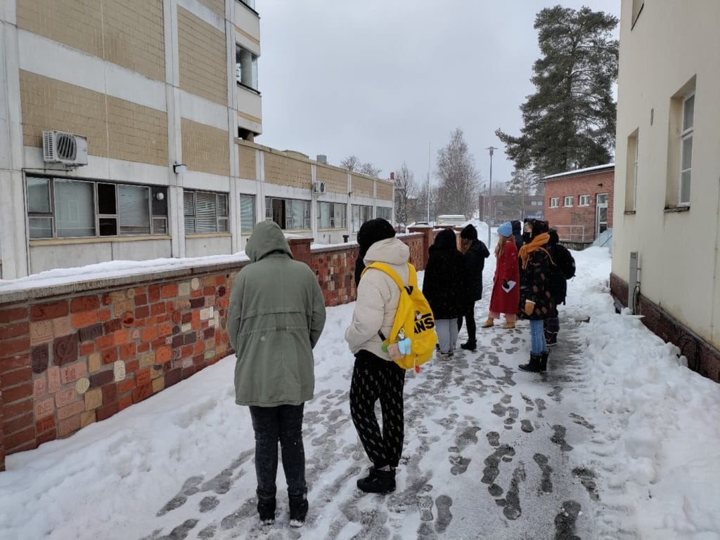 Opiskelijaryhmä ulkona Taidekehän Puumerkkitiilimuuurin luona.