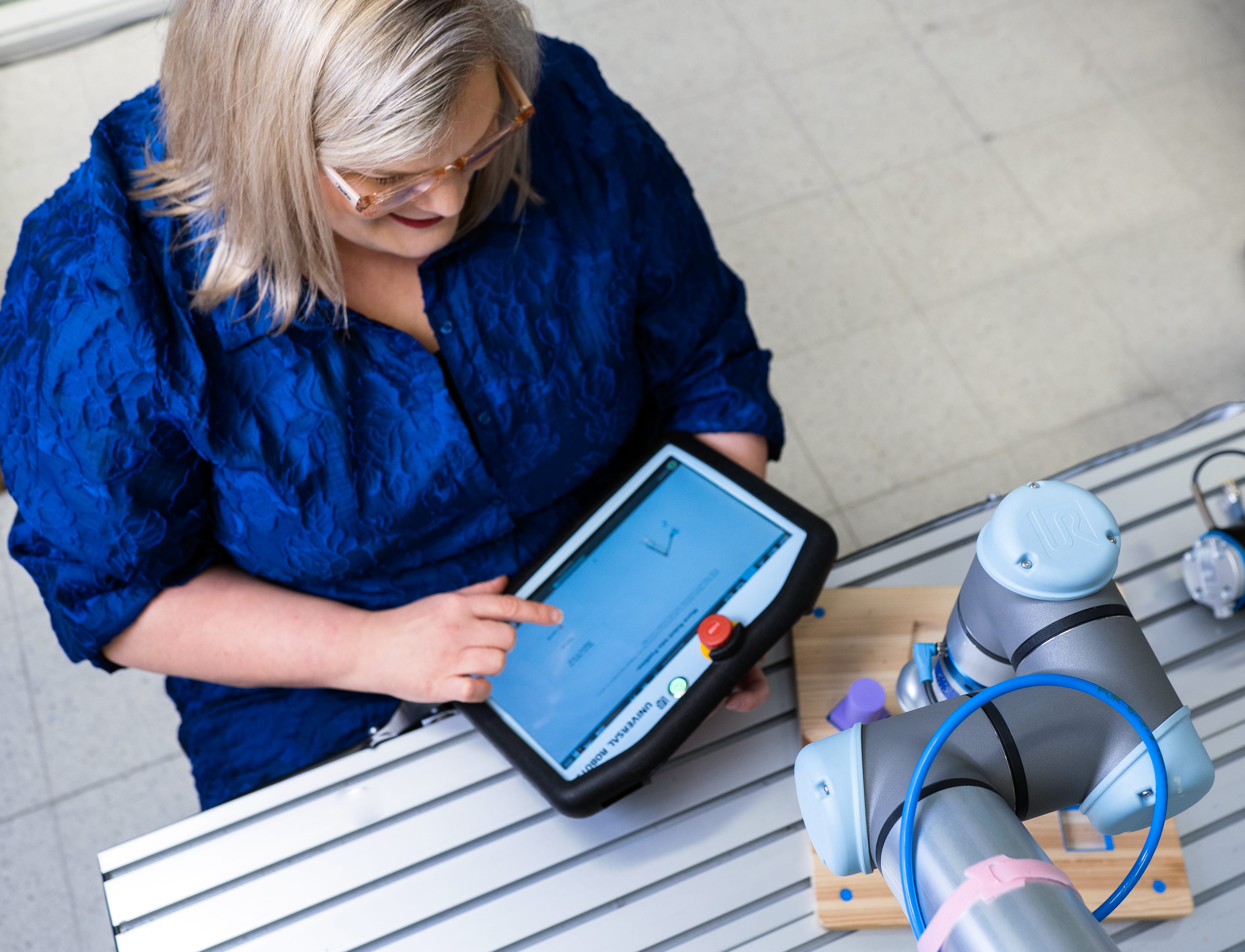 A woman using a collaboration robot on a tablet.