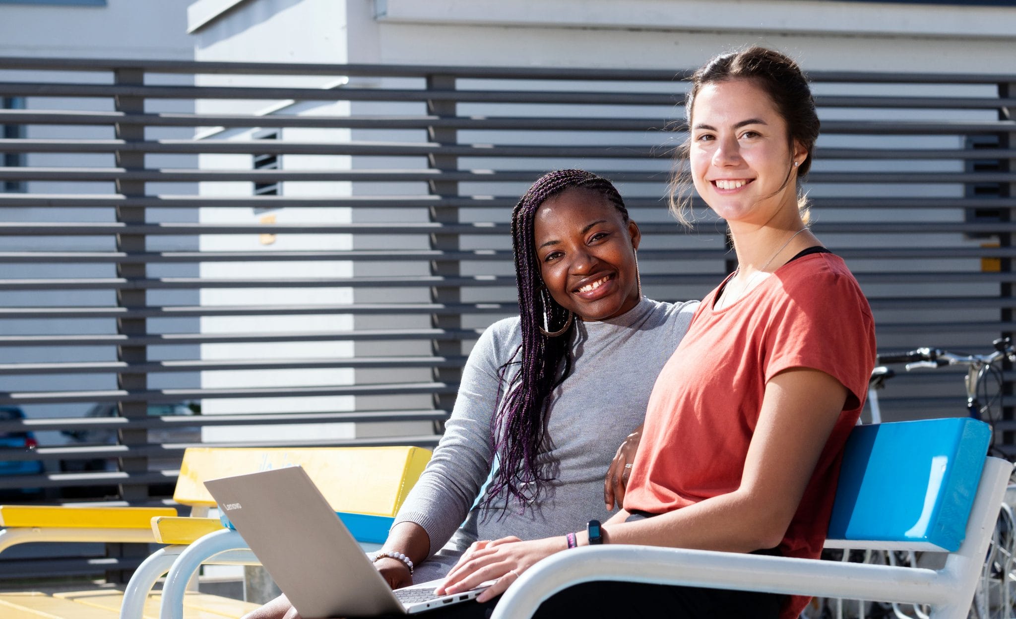 Smiling students sitting on a bench.
