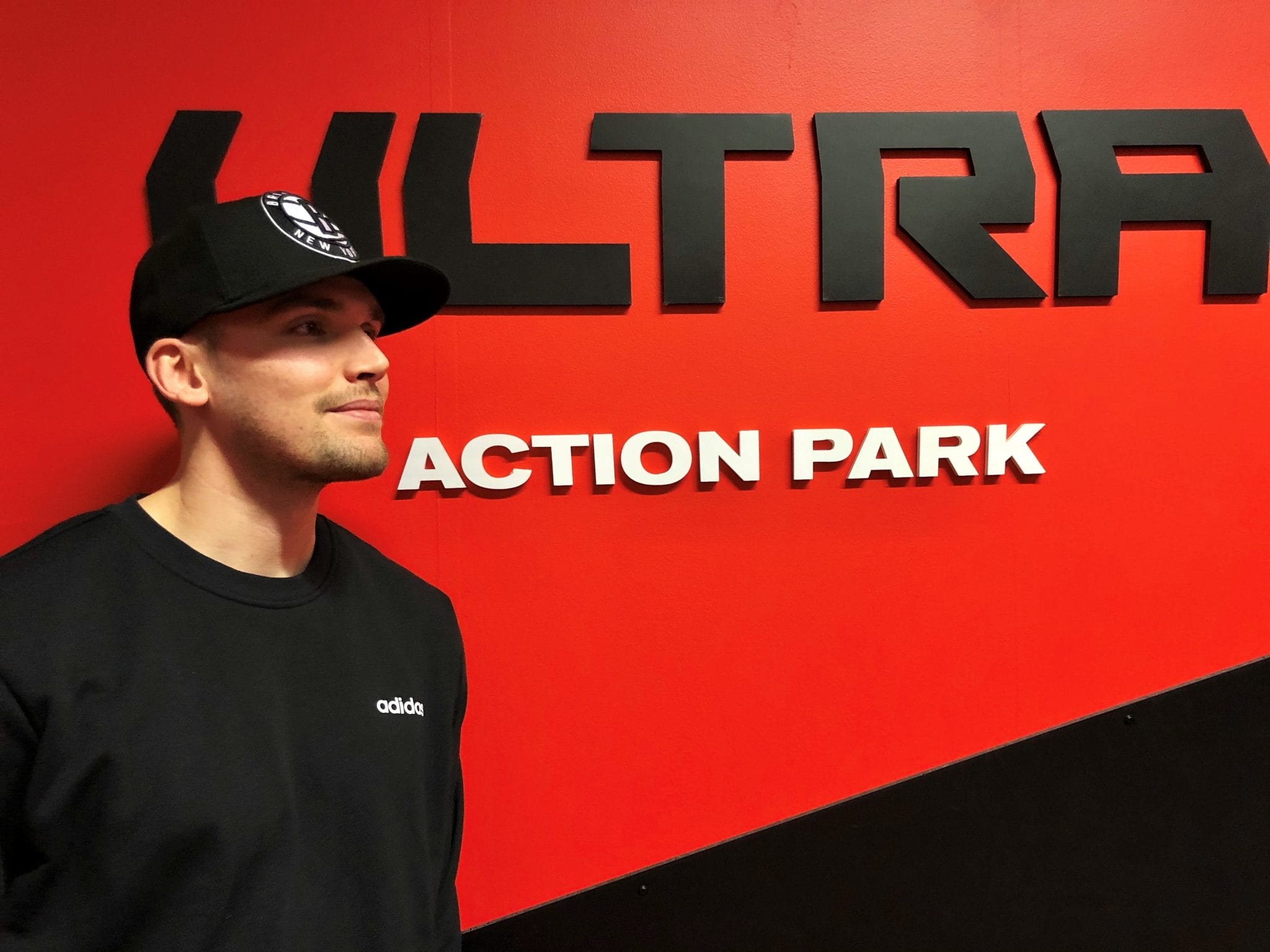 Tino Lehtonen seisoo Ultra Action Parkin logon edessä.