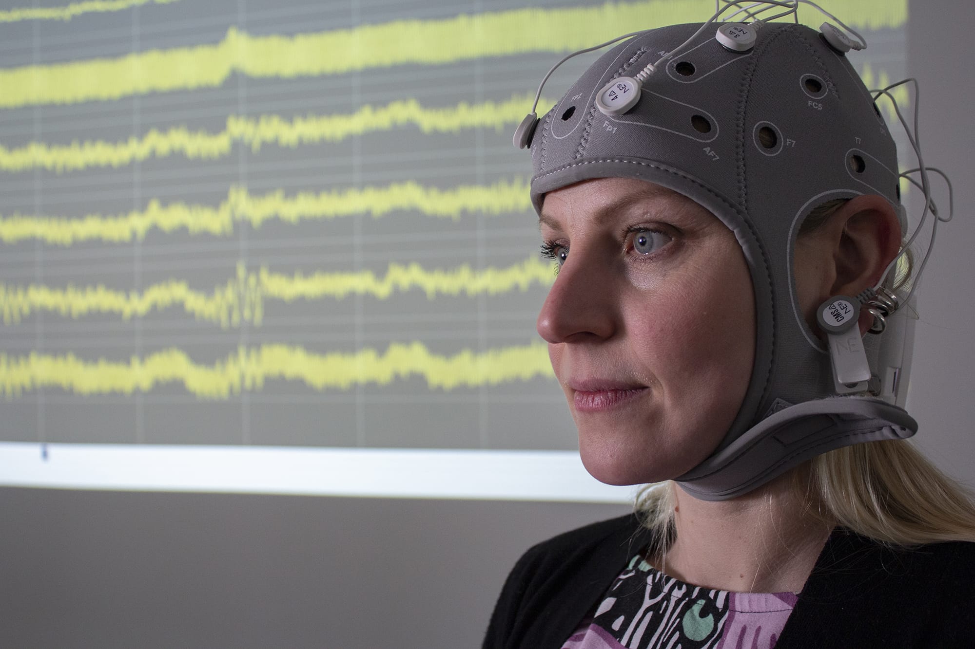 Close-up of a woman wearing a hat that reads the brainwaves on her head.