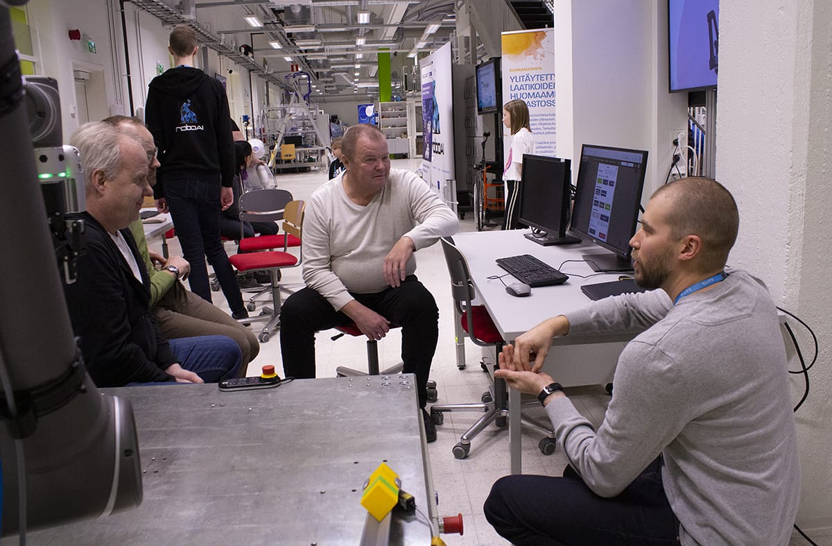Mies esittelee ryhmälle yhteistyörobotin toimintaa.