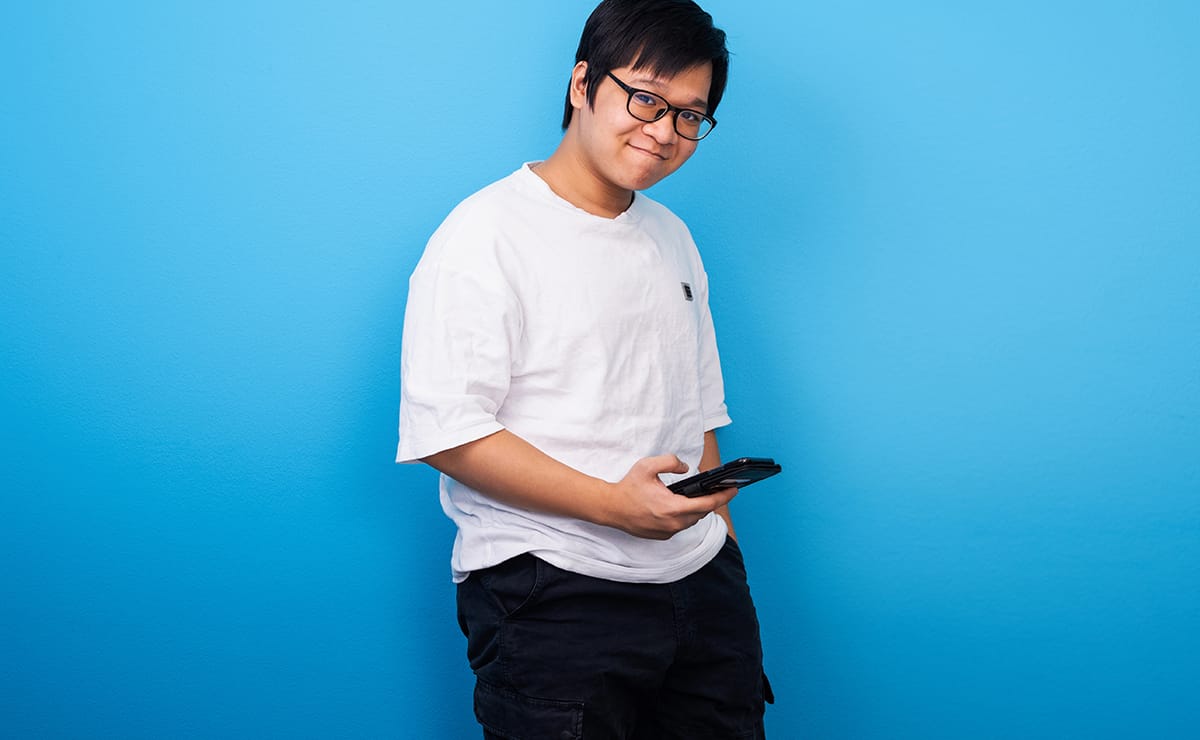 A student smiling, a phone in hand.
