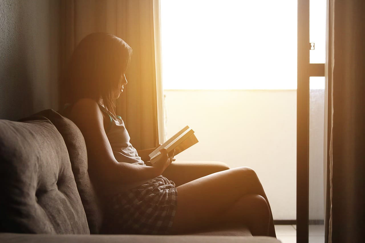 A woman is reading a book by the window.