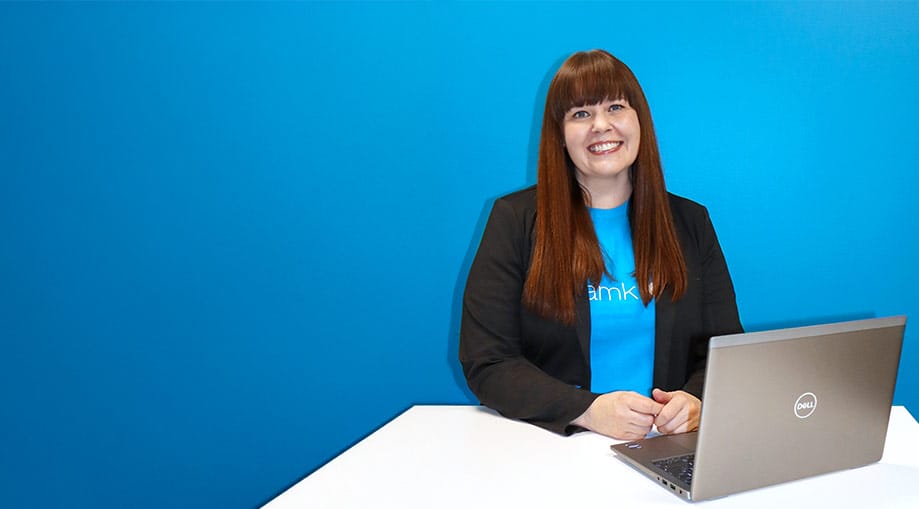 Partnership Manager Tanja Vaitiniemi stands in front of the blue wall.