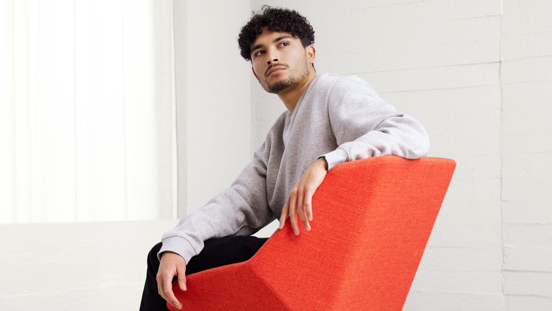 A man is sitting in a red chair.